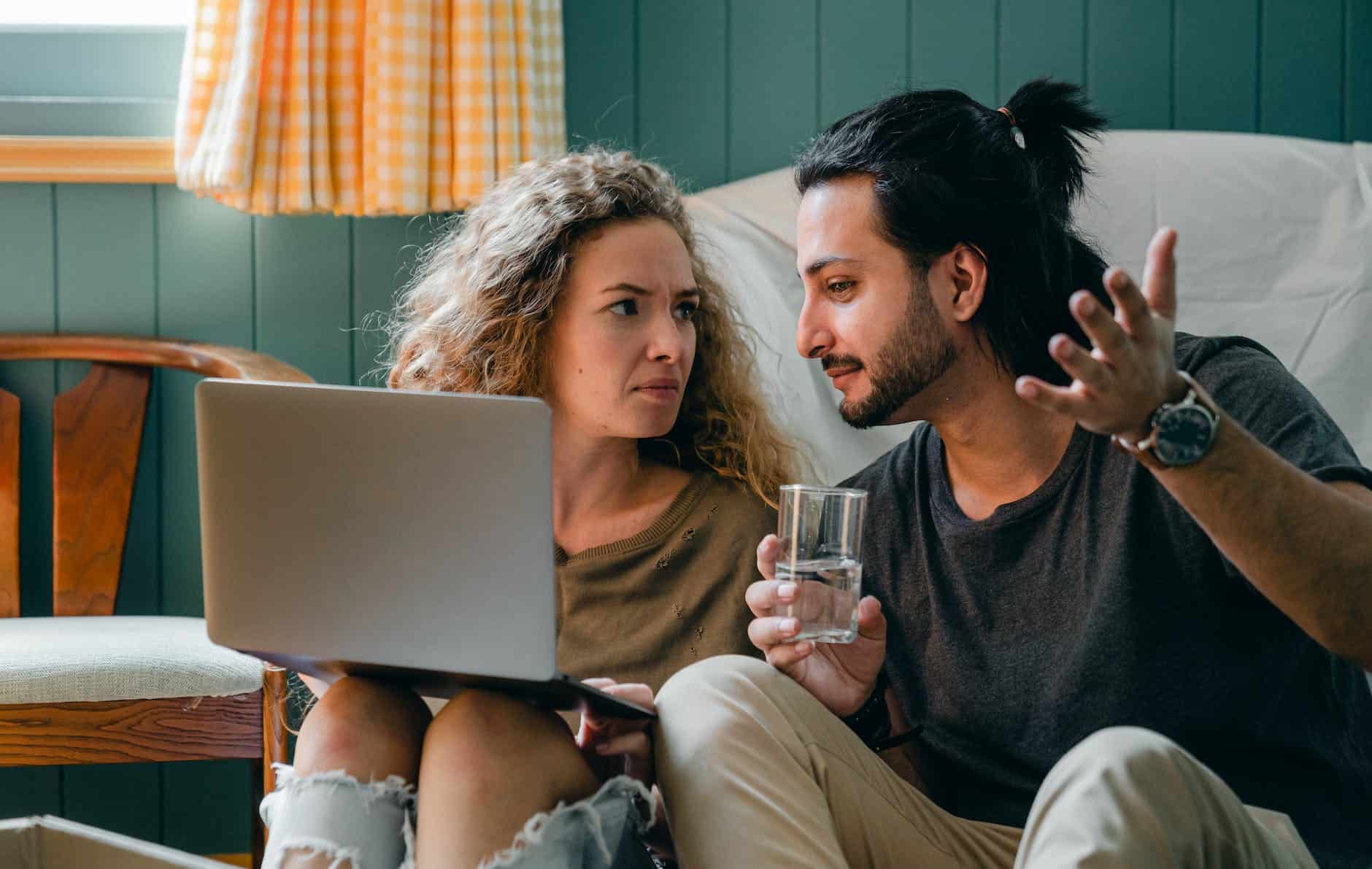 pensive couple with laptop sitting on floor