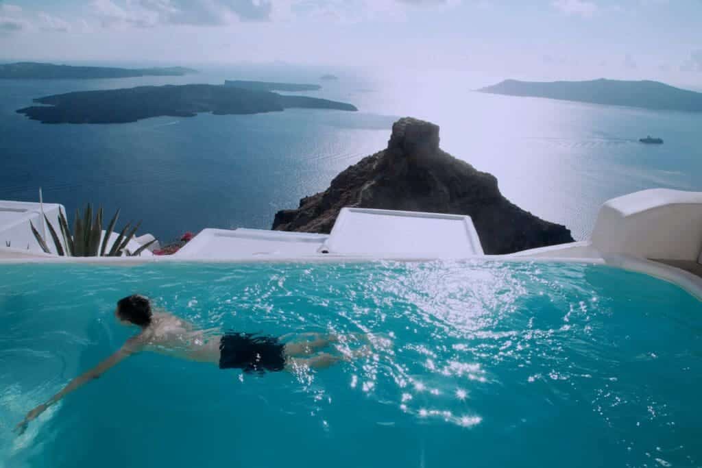 Man Wearing Black Shorts Swimming in Infinity Pool