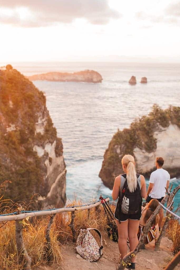 Traveling people walking down to blue sea at sunset