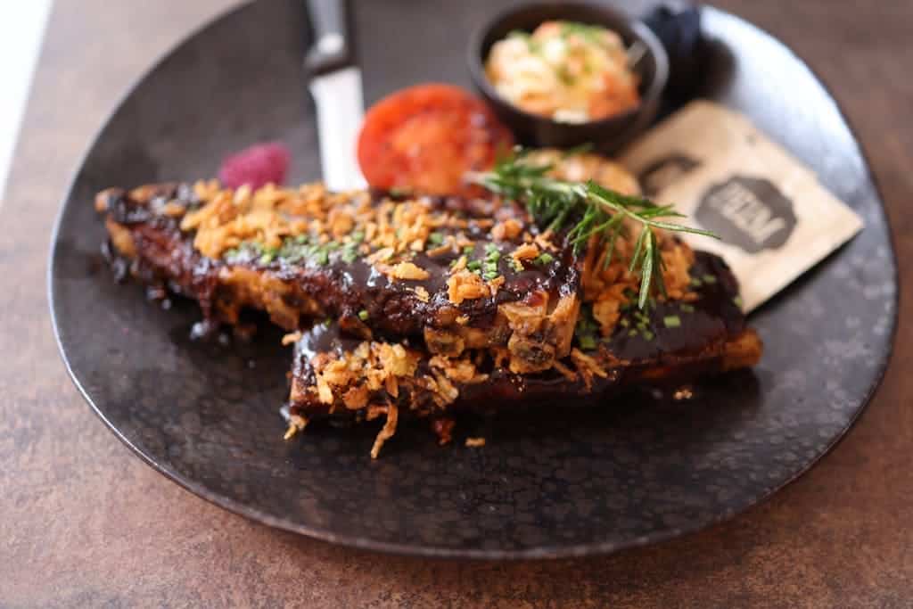 A plate with ribs and vegetables on it