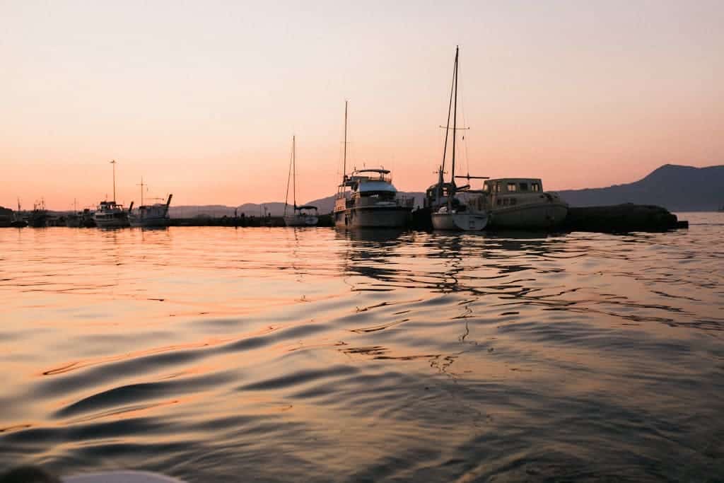 Rippling sea water with reflecting dusky sky with boats and yachts in dusky light