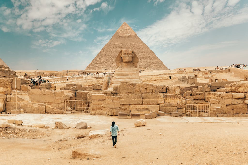 Back view of unrecognizable man walking towards ancient monument Great Sphinx of Giza