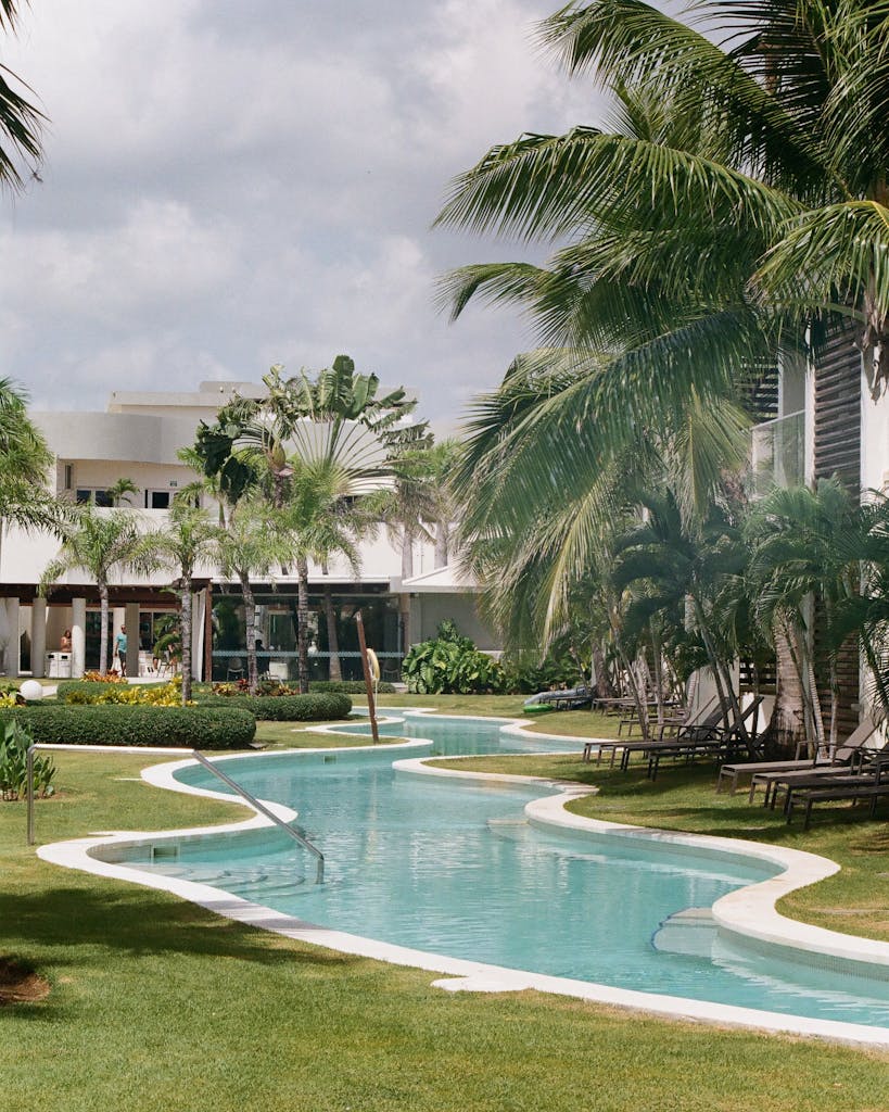 Elegant tropical resort featuring a winding pool, palm trees, and relaxing atmosphere.