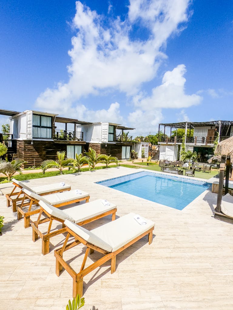 Relaxing poolside view at a luxury resort featuring lounge chairs and blue sky.