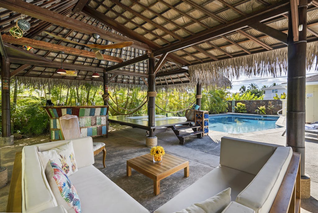 Tropical outdoor patio featuring a cabana, seating area, and swimming pool, perfect for luxury relaxation.