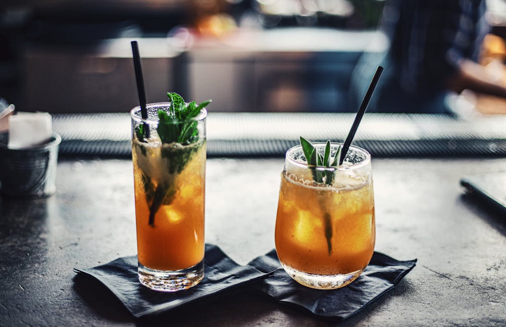 Two chilled cocktails with mint and ice on a bar counter, garnished with fresh mint leaves.